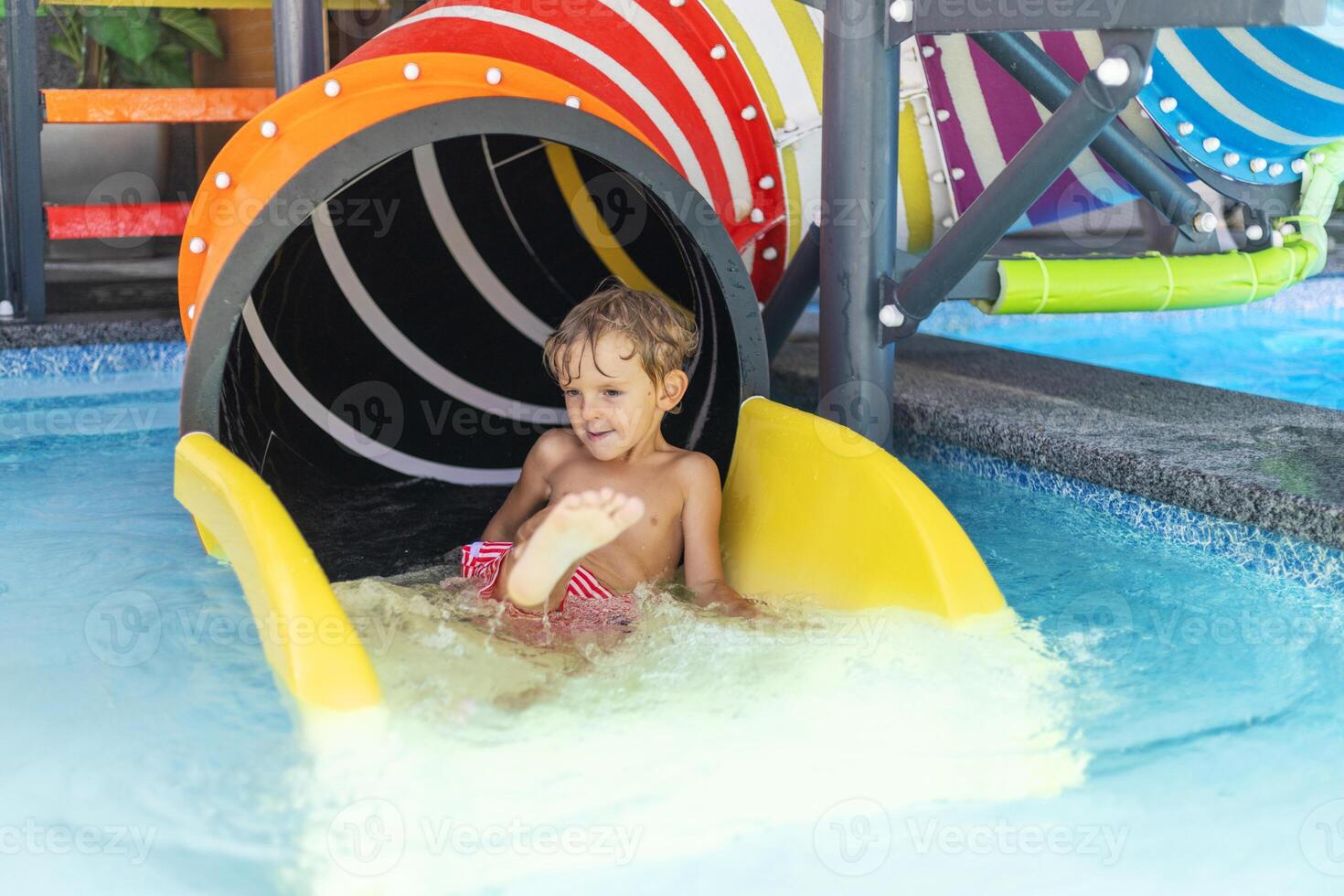 Child on colorful water slide exit photo