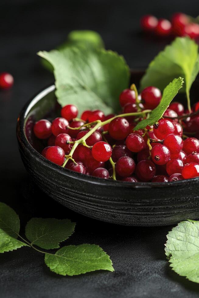 Red currants in a bowl on a black table photo