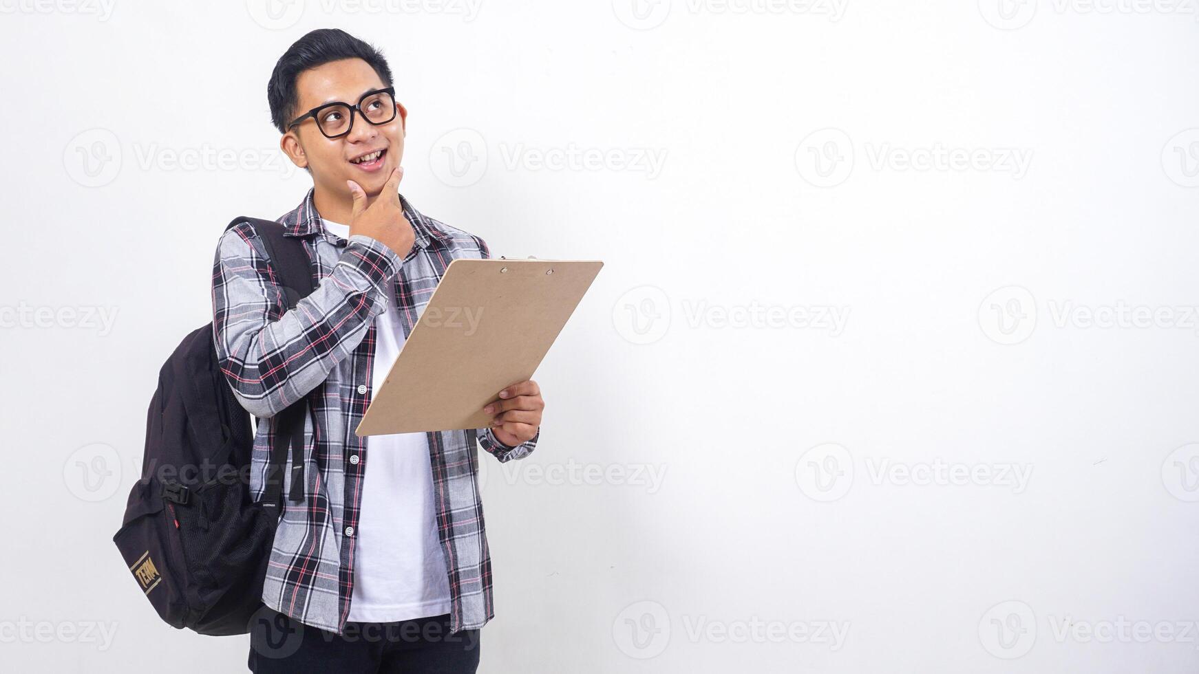 Portrait of smart young Asian male college student with a backpack holding clipboard isolated on white background photo