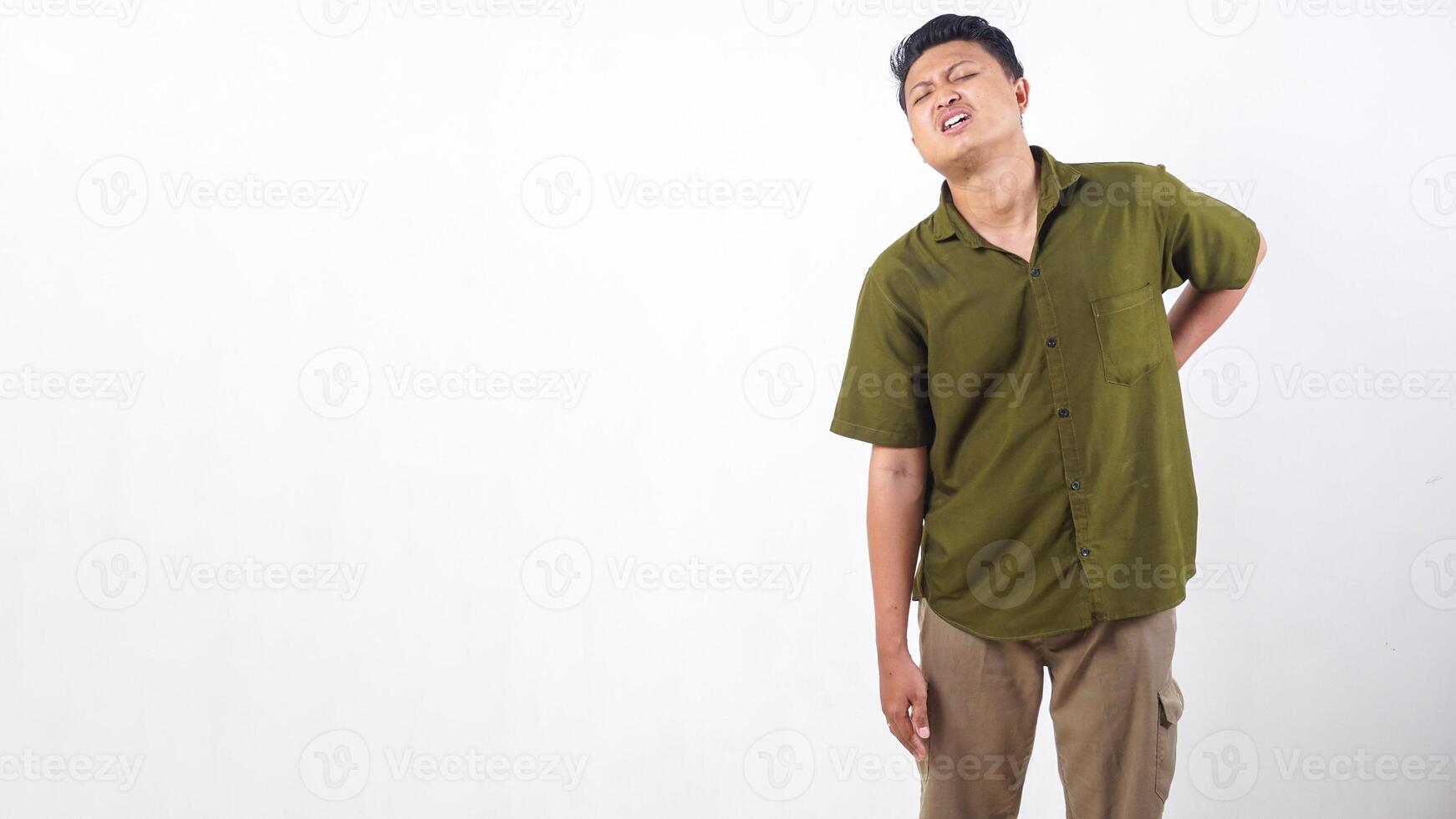 Asian man experiencing intense back pain, holding his back in agony isolated on white background photo