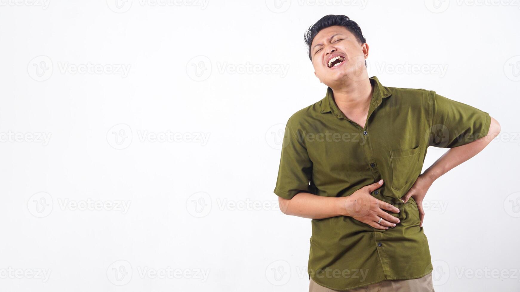 Asian male in distress from abdominal pain holding stomach isolated on white background photo
