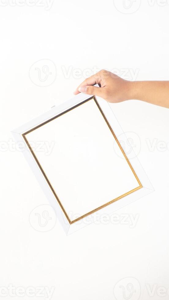Hand holding simple white colored wooden picture frame isolated on white background photo