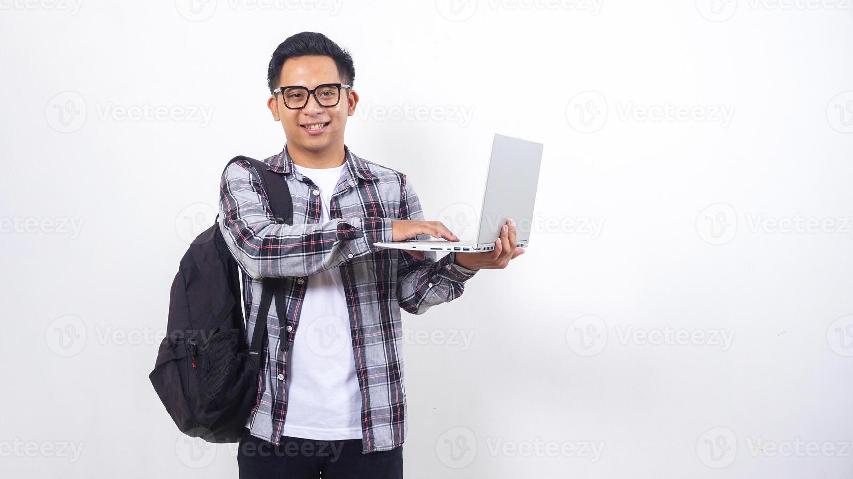 Portrait of excited young Asian male college student with a backpack and touching open laptop notebook isolated on white background photo