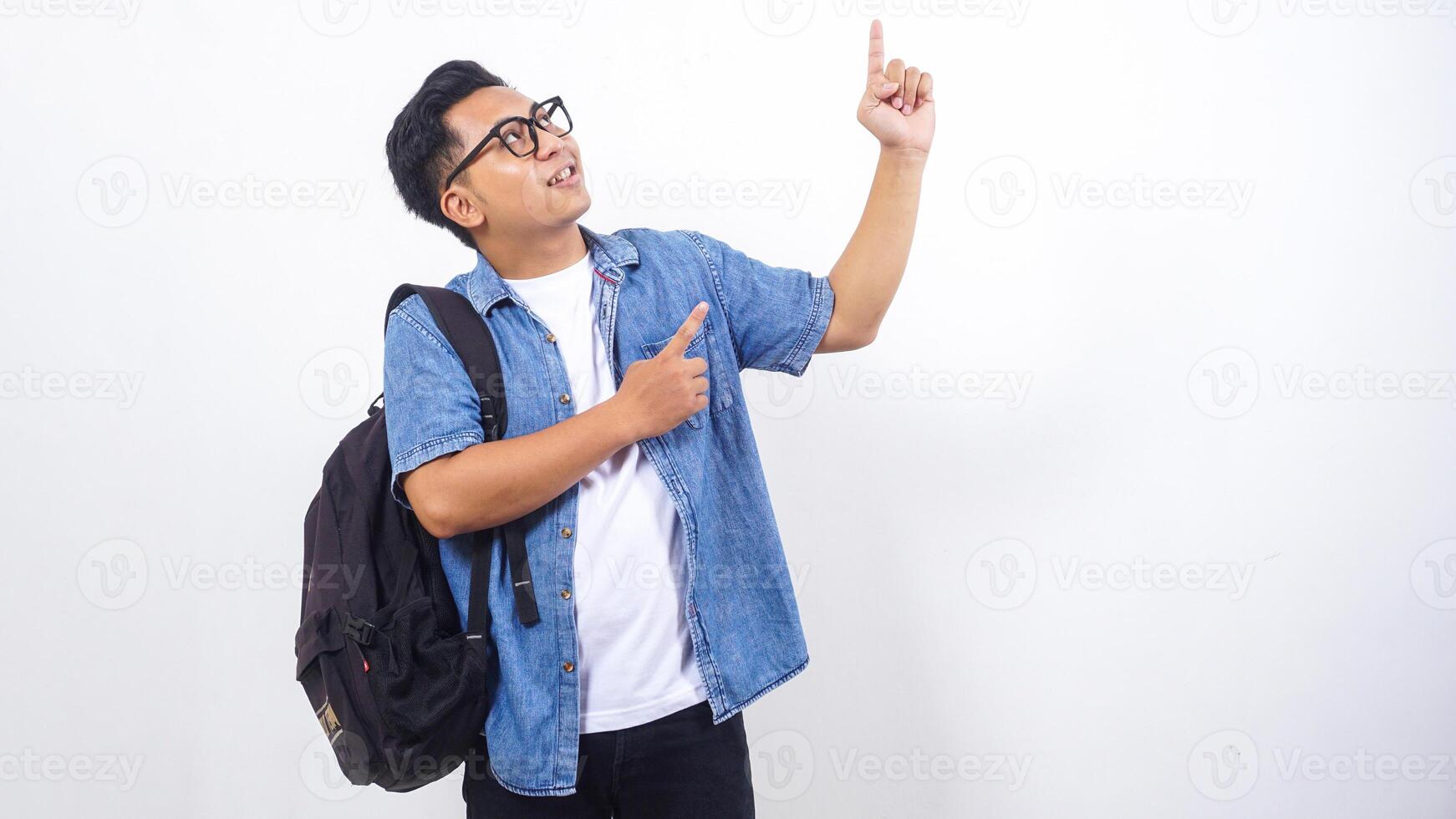 Portrait of handsome young Asian male university student in casual outfit with backpack is presenting empty space isolated on white background photo