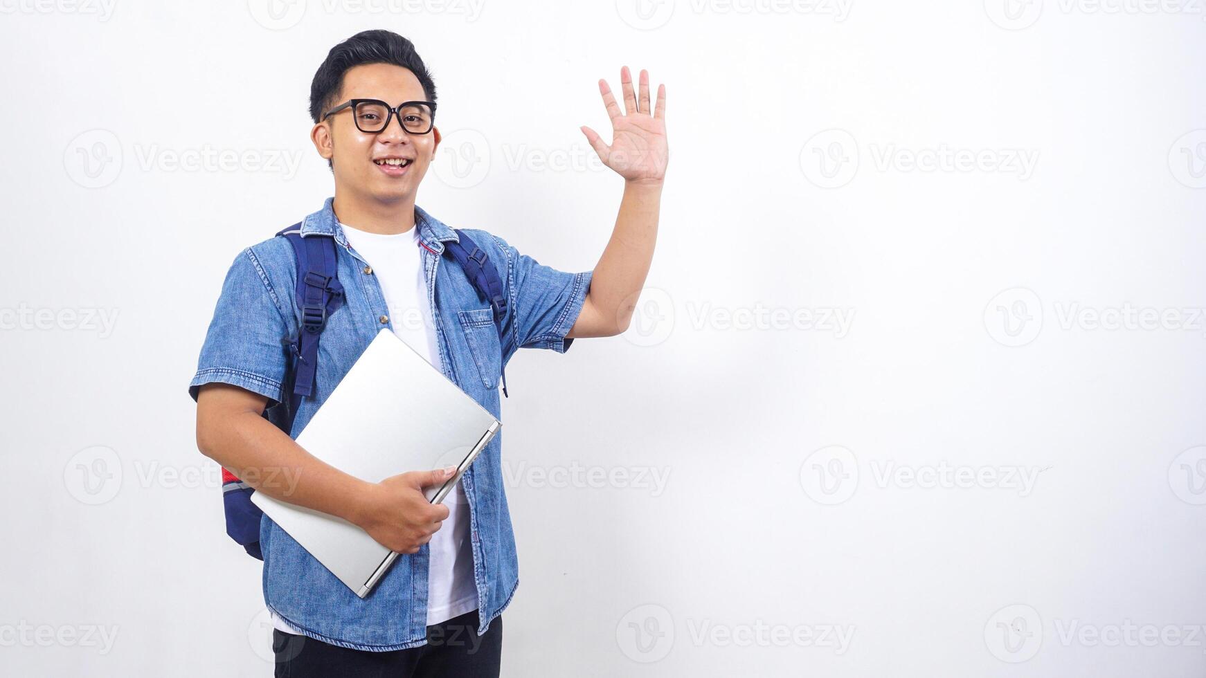 Handsome young Asian male university student in casual outfit with backpack and laptop isolated on white background with copy space photo