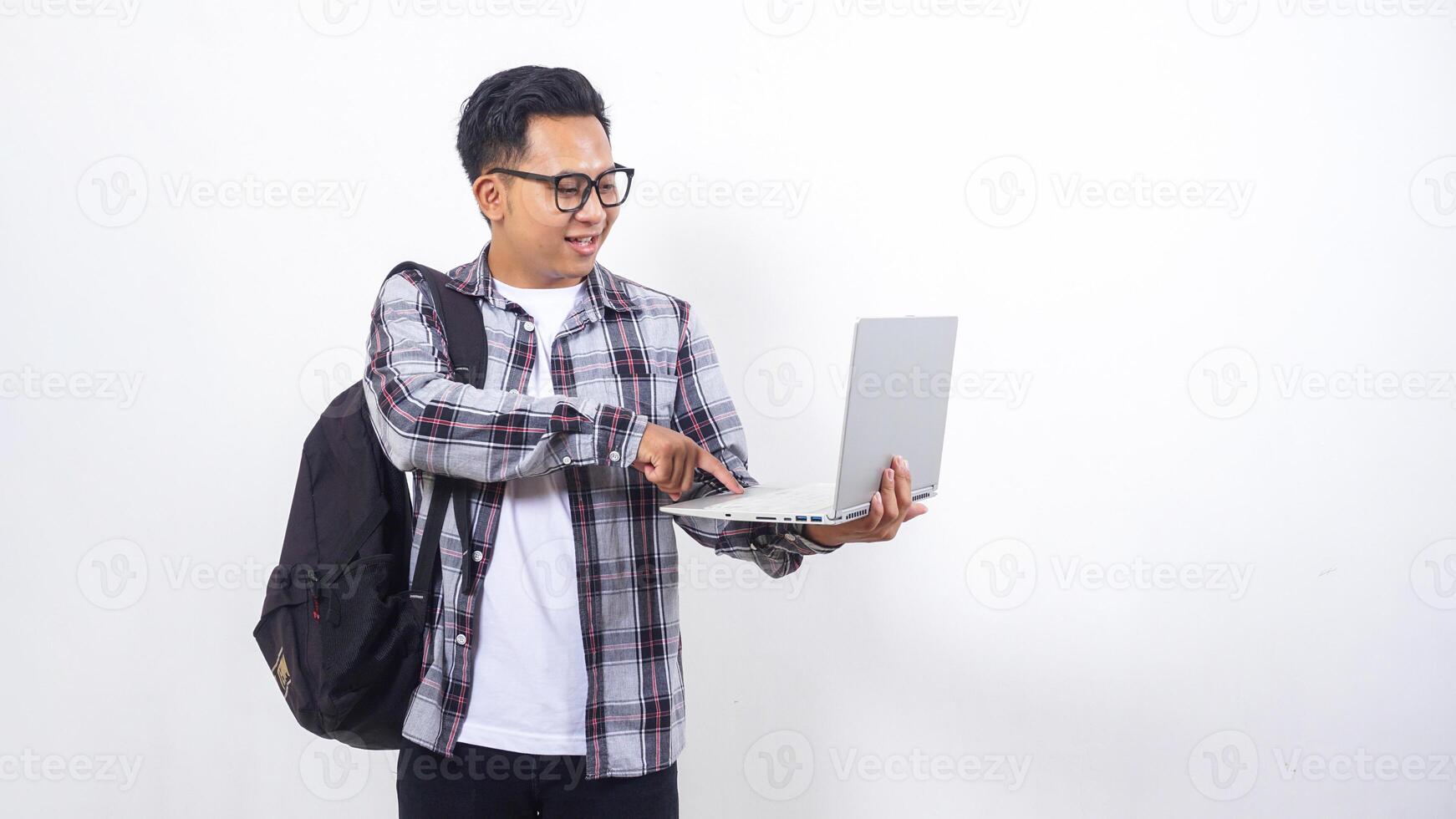 Portrait of young Asian male college student with a backpack and touching open laptop notebook isolated on white background photo