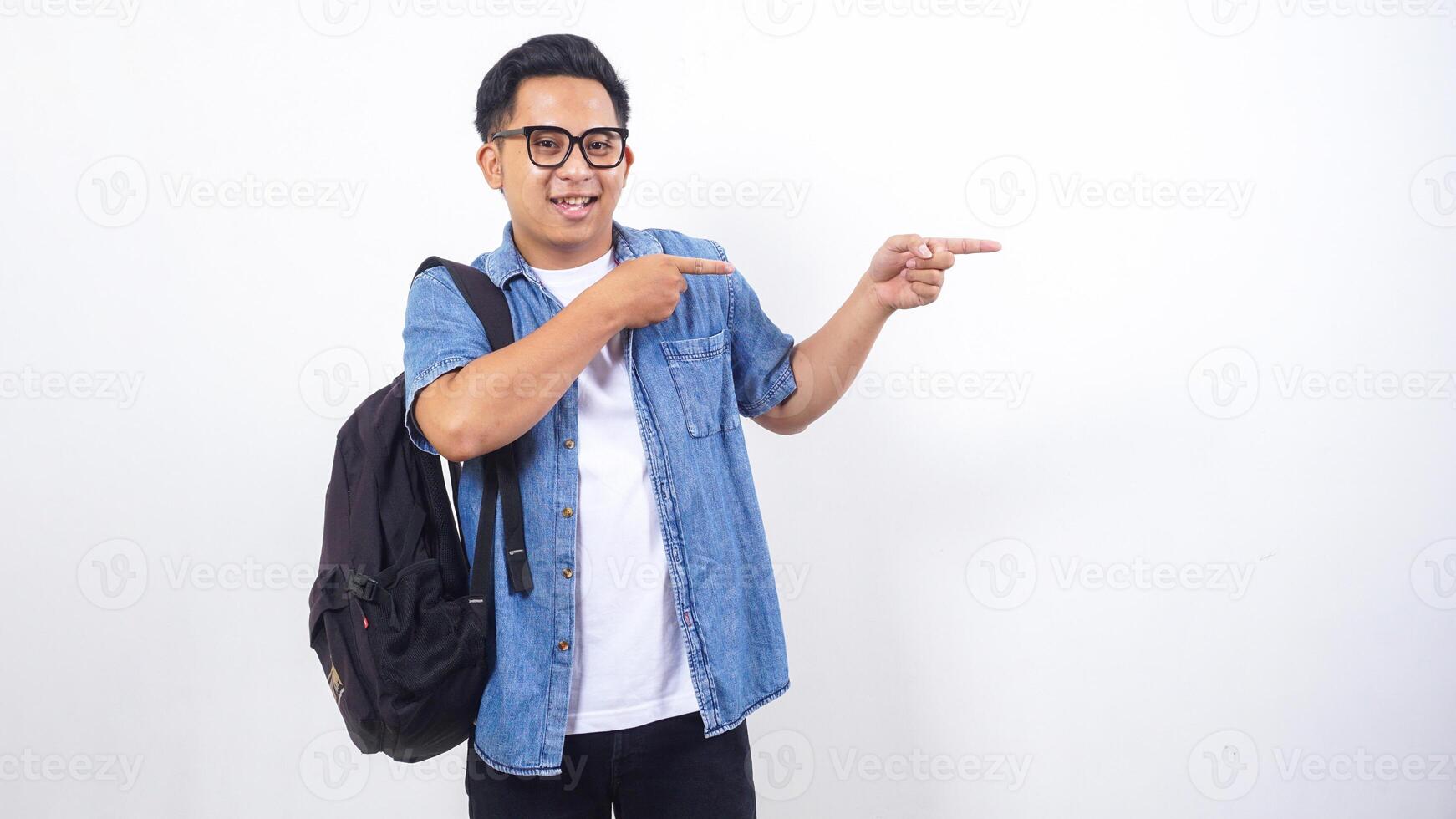 Portrait of young Asian male university student in casual outfit with backpack is presenting empty space isolated on white background photo