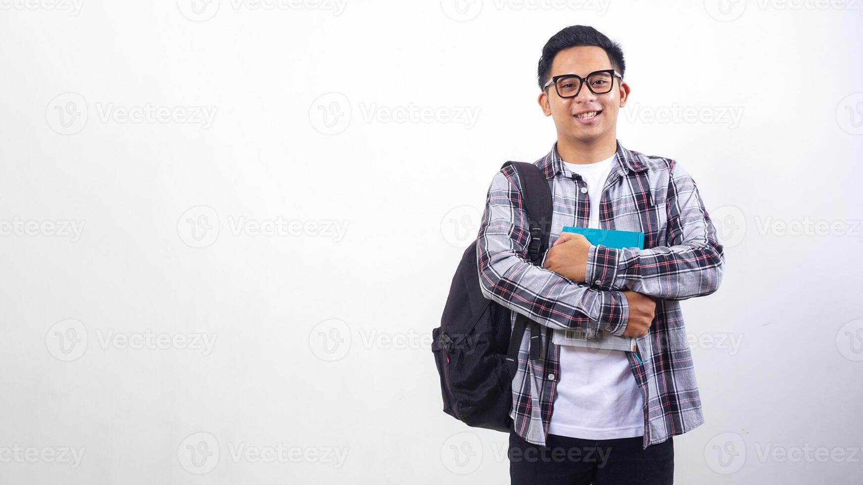 Handsome young Asian male university student with a backpack holding books in front of his chest standing isolated on white background photo