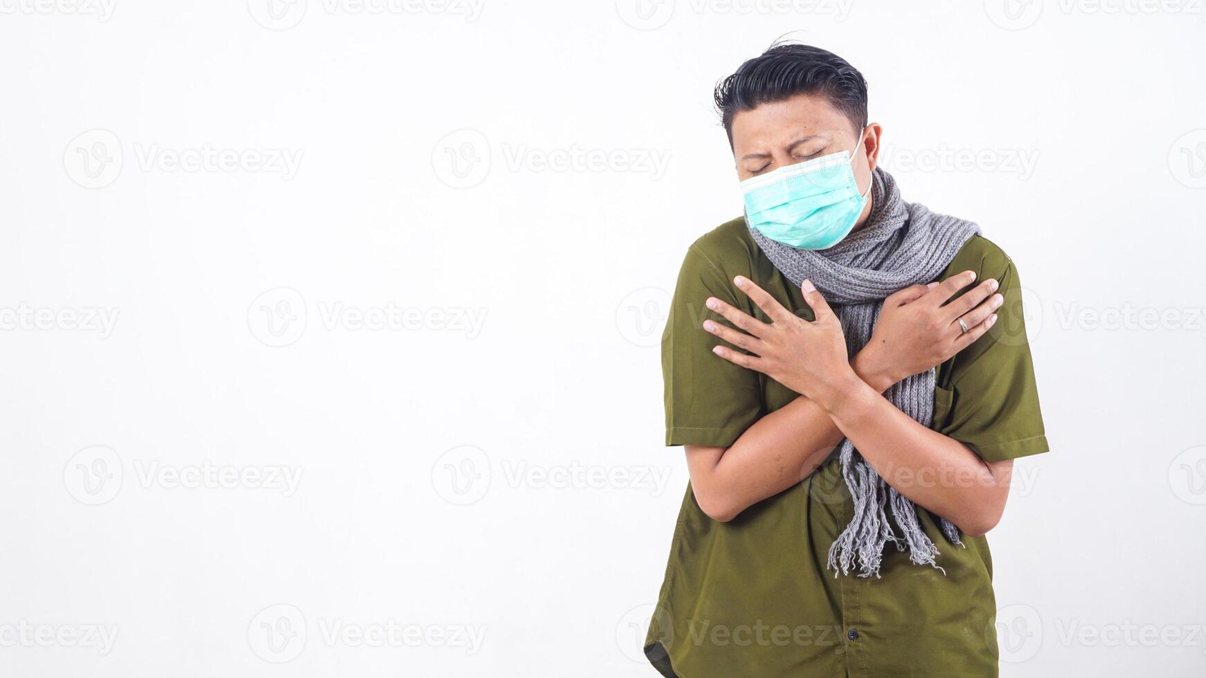 Sick man in protective mask and wearing wool scarf showing fever symptoms isolated on white background photo