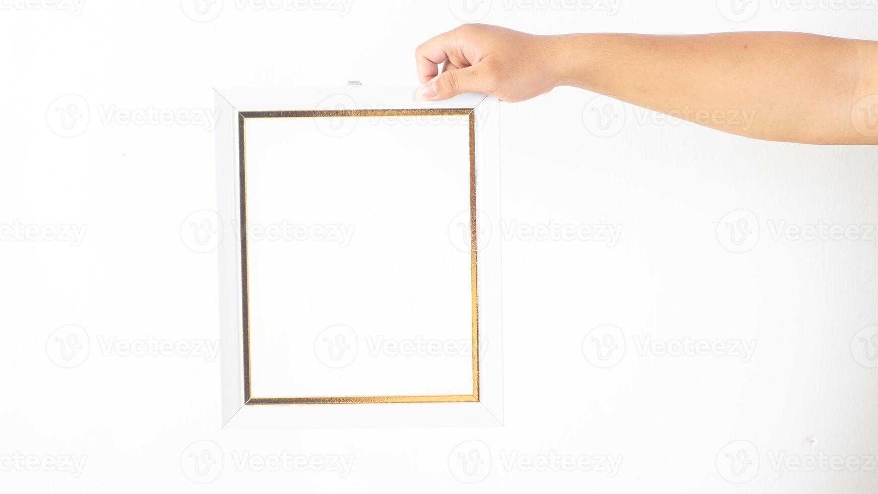 Hand holding simple white colored wooden photo frame isolated on white background