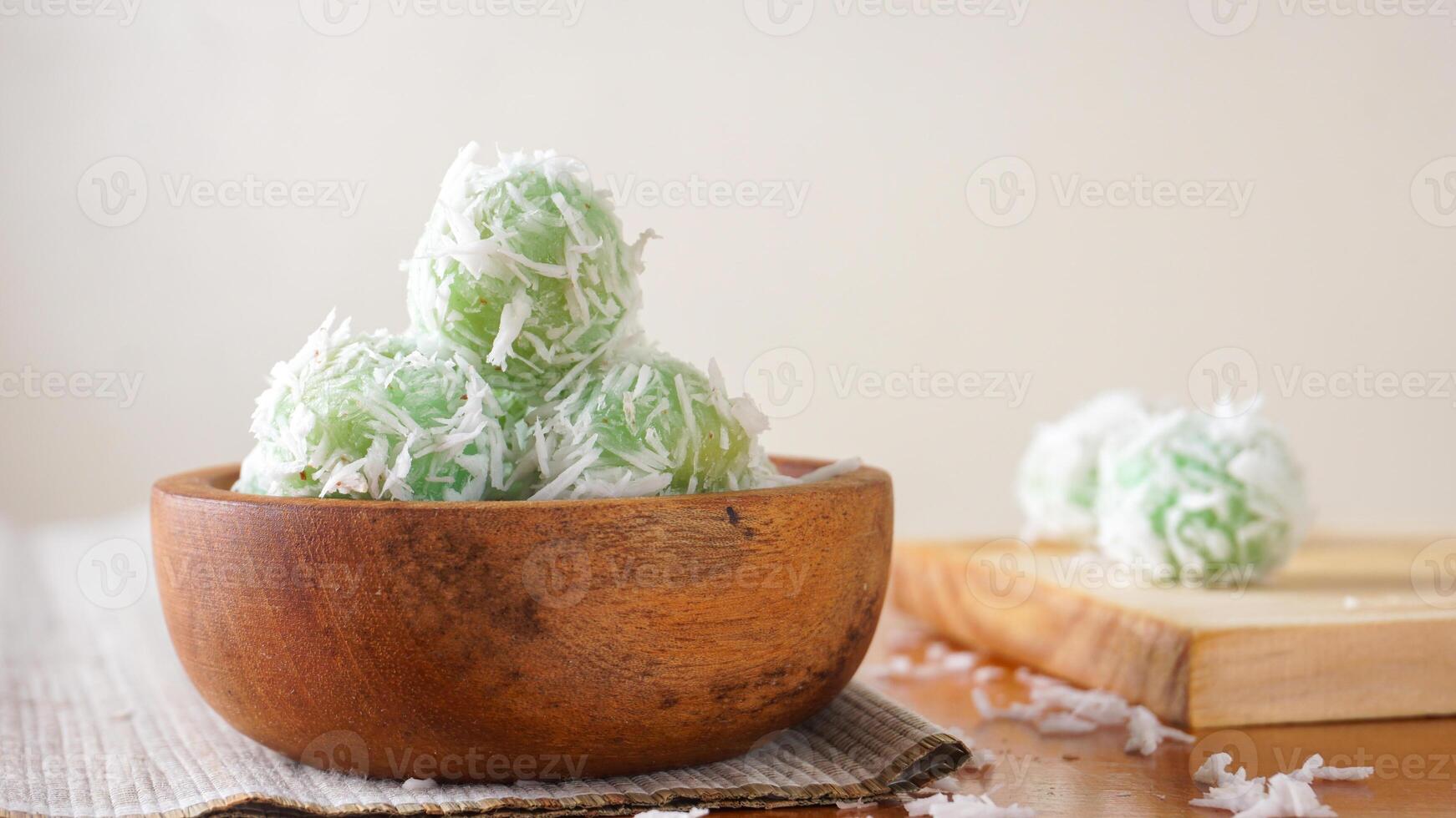 A traditional Indonesian snack made from green sticky rice balls called Klepon on wooden bowl isolated on white background photo