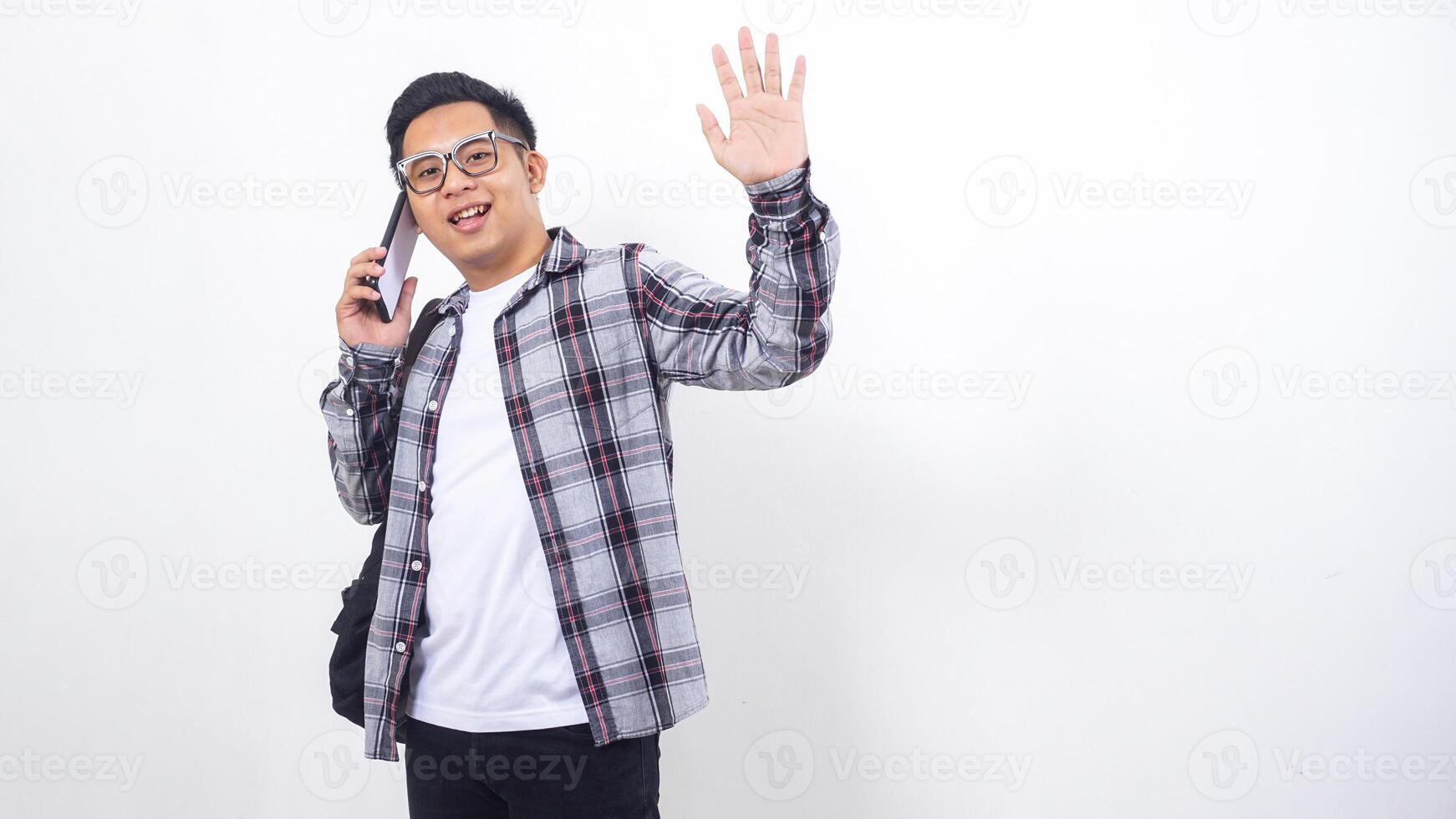 Handsome young Asian male college student with a backpack talking on the smartphone isolated on white background photo