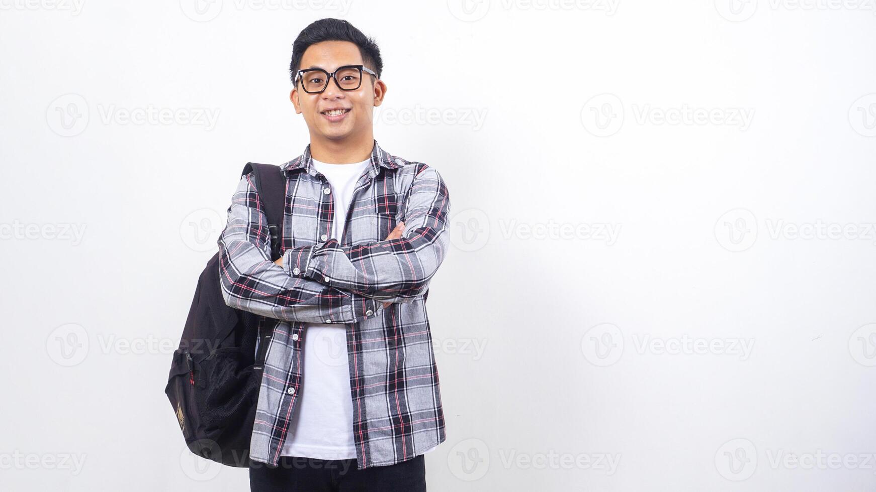 Happy young Asian male college student with a backpack and crossing his arms in front of his chest isolated on white background photo
