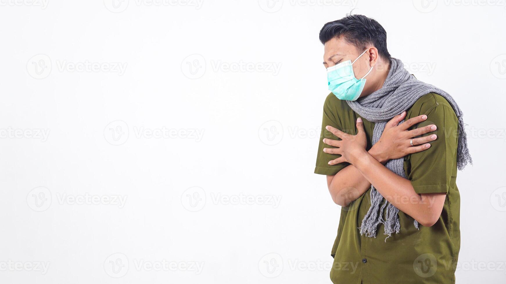 Sick adult man in protective mask and wearing wool scarf showing fever symptoms isolated on white background photo