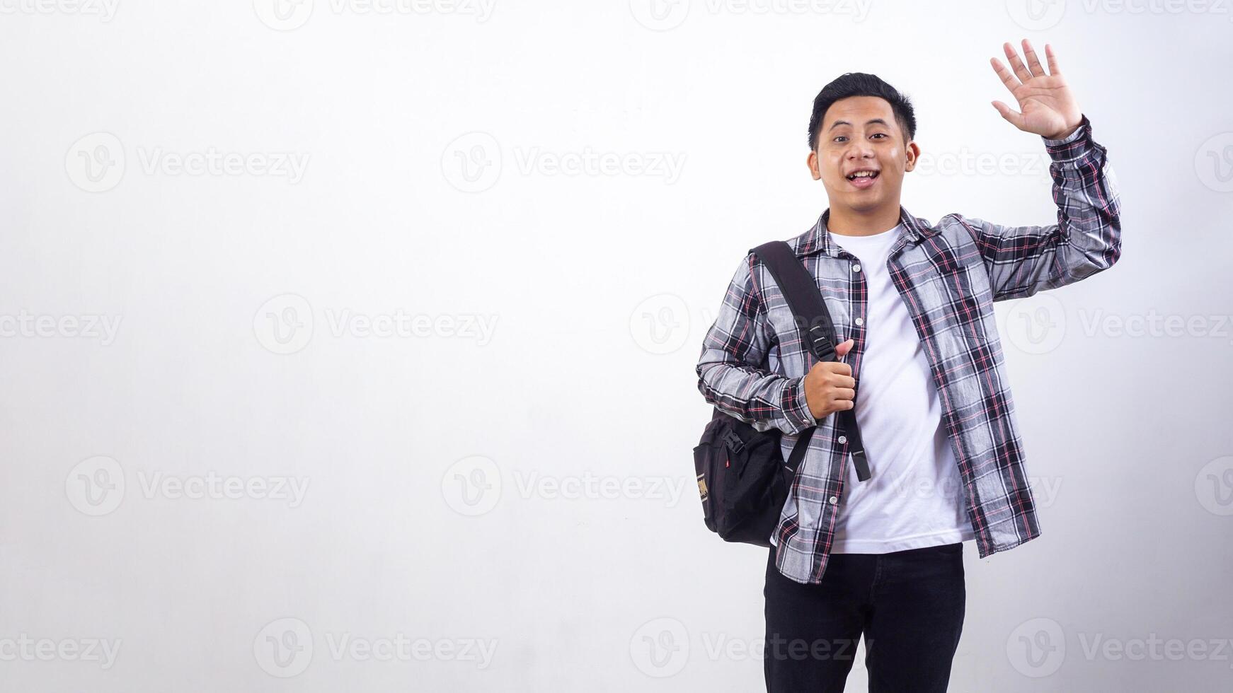 Handsome young Asian male college student with a backpack and showing gesture of greeting isolated on white background photo