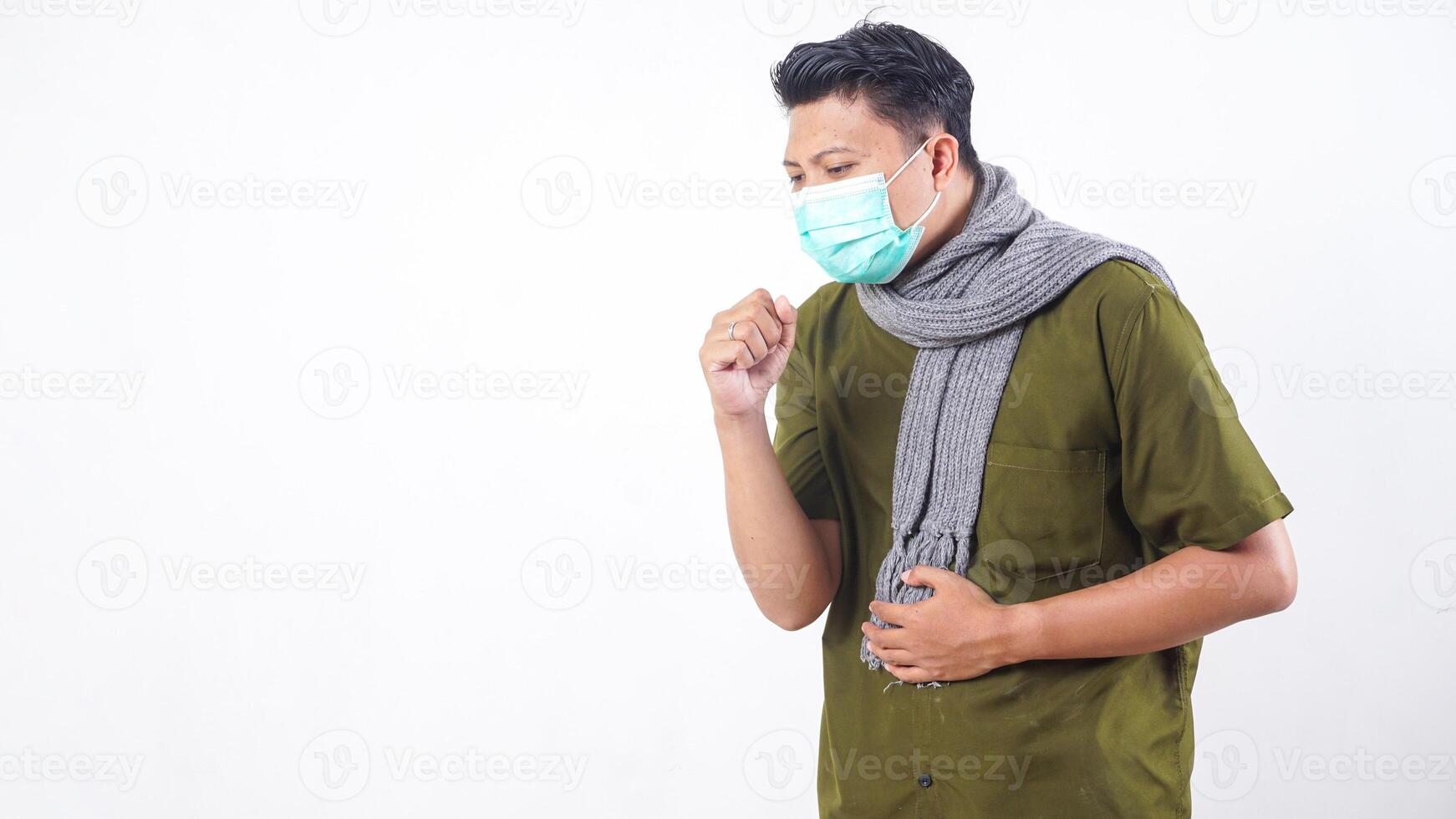 Sick adult man in protective mask and wearing wool scarf struggling with cough isolated on white background photo