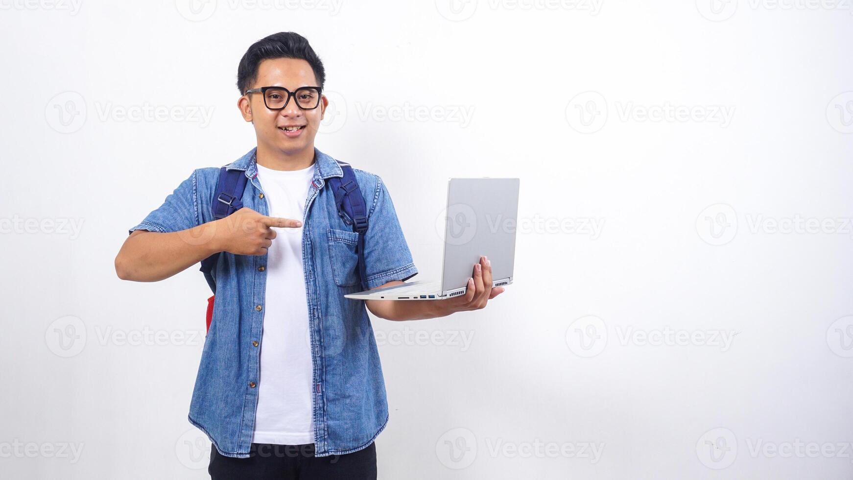 Smart young Asian male university student in casual outfit with backpack and open laptop isolated on white background with copy space photo