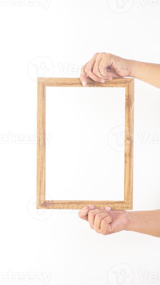 Hand holding empty wooden picture frame isolated on white background photo