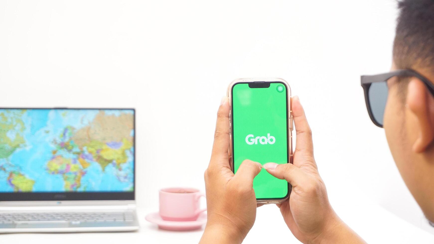 Yogyakarta, Indonesia, 2025 - Man holds smartphone showing Grab, on-demand service platforms in Indonesia application on the screen isolated on white background photo