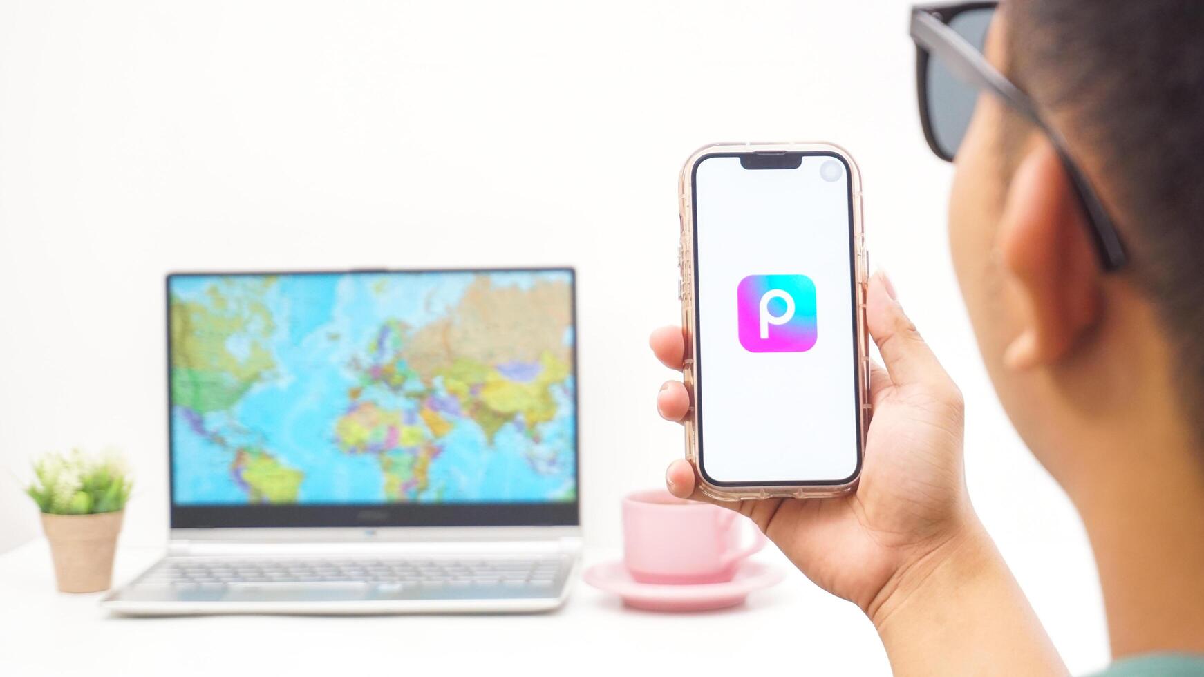 Yogyakarta, Indonesia, 2025 - Man holding smartphone with Picsart, creative editing platform application on the screen isolated on white background photo