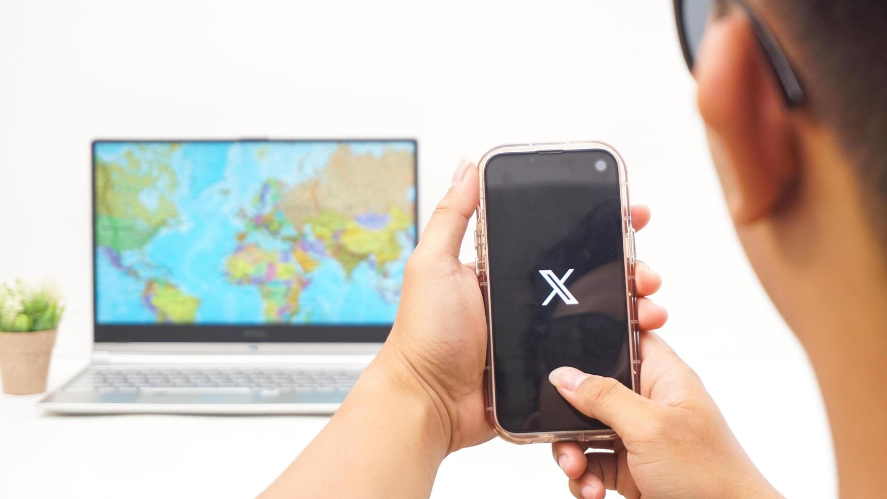 Yogyakarta, Indonesia, 2025 - Man holding smartphone showing X former Twitter social media platform application on the screen isolated on white background photo