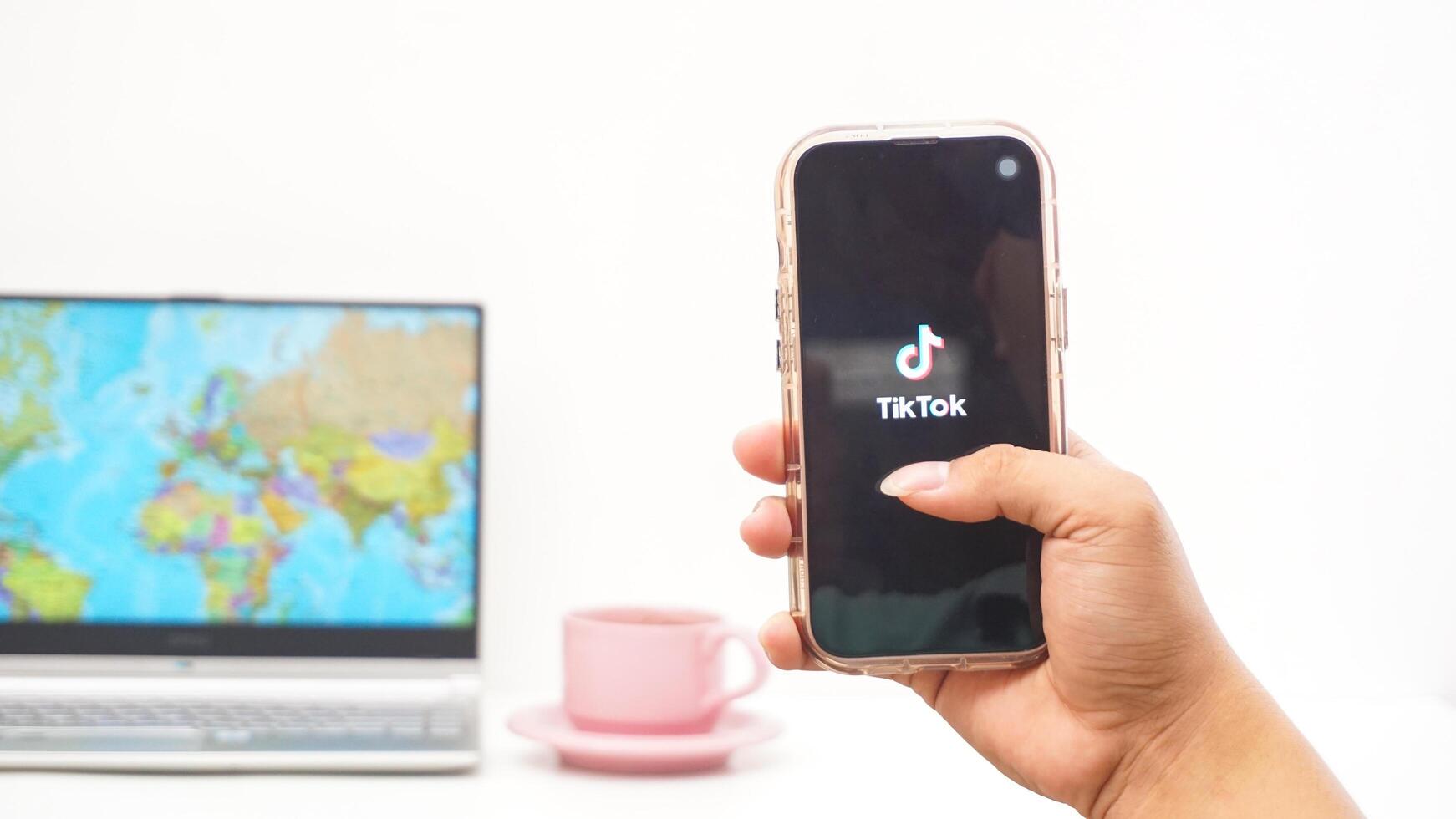Yogyakarta, Indonesia, 2025 - Man holding smartphone with Tiktok, social and entertainment platform application on the screen isolated on white background photo