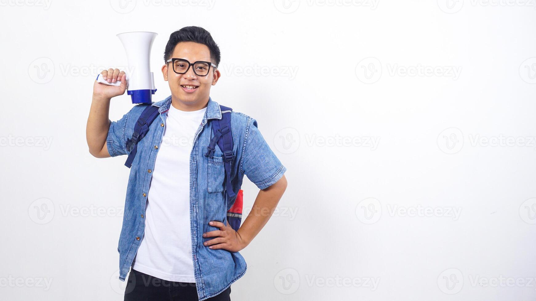 Close up of young Asian male university student in casual outfit with backpack is holding megaphone isolated on white background photo