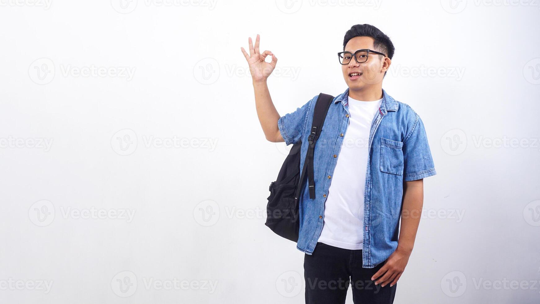 Portrait of happy young Asian male university student in casual outfit with backpack isolated on white background with copy space photo