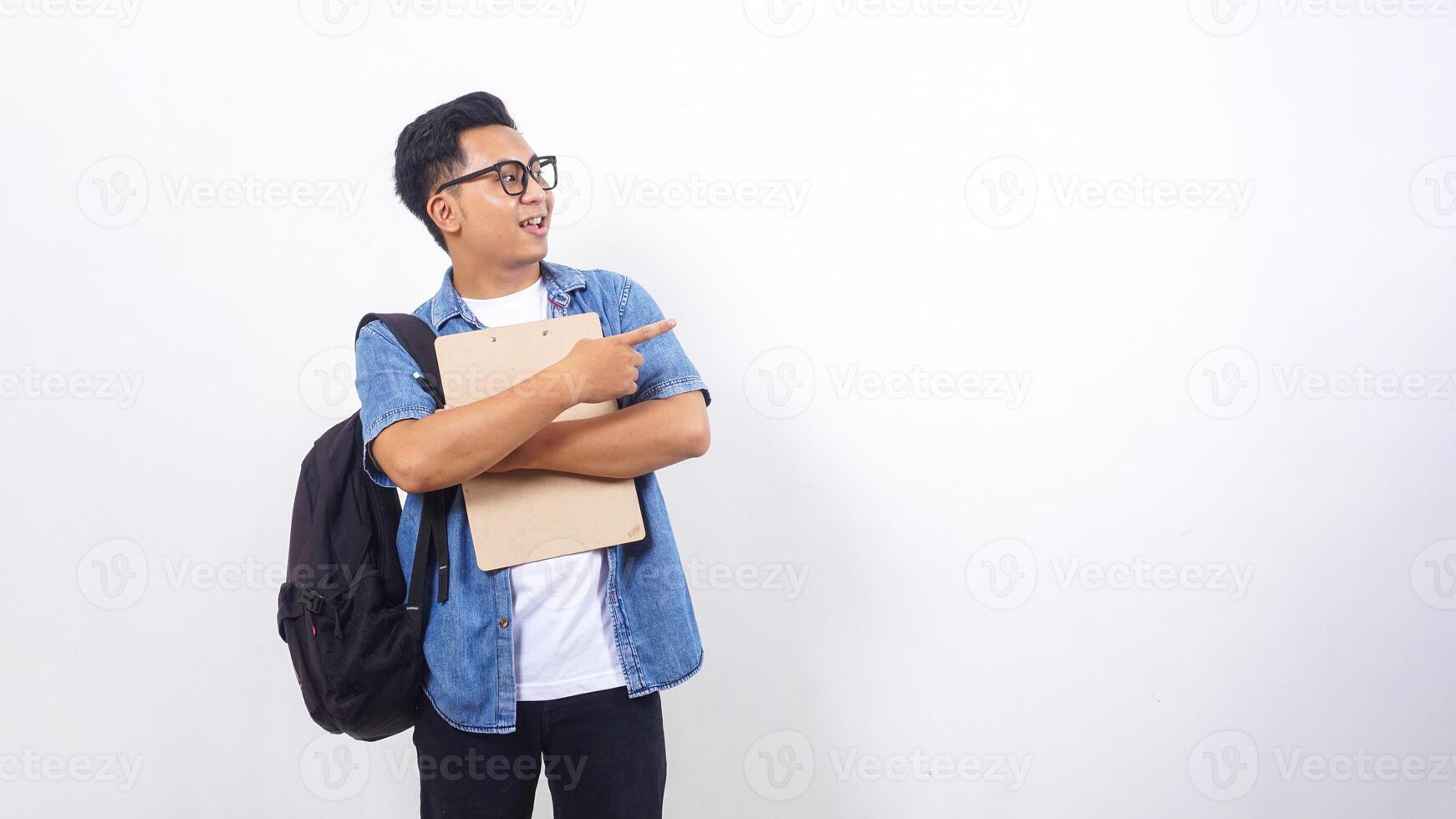 Smart young Asian male university student in casual outfit with backpack and holding clipboard isolated on white background photo