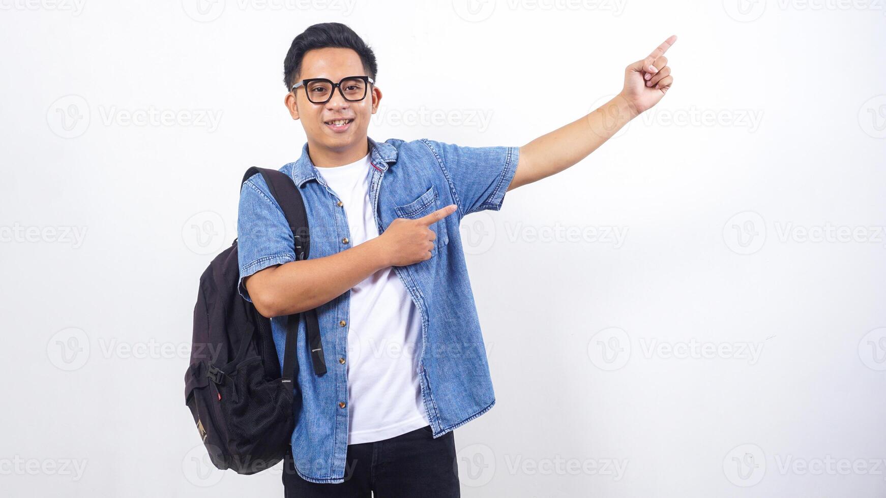 Portrait of happy young Asian male university student in casual outfit with backpack is presenting empty space isolated on white background photo