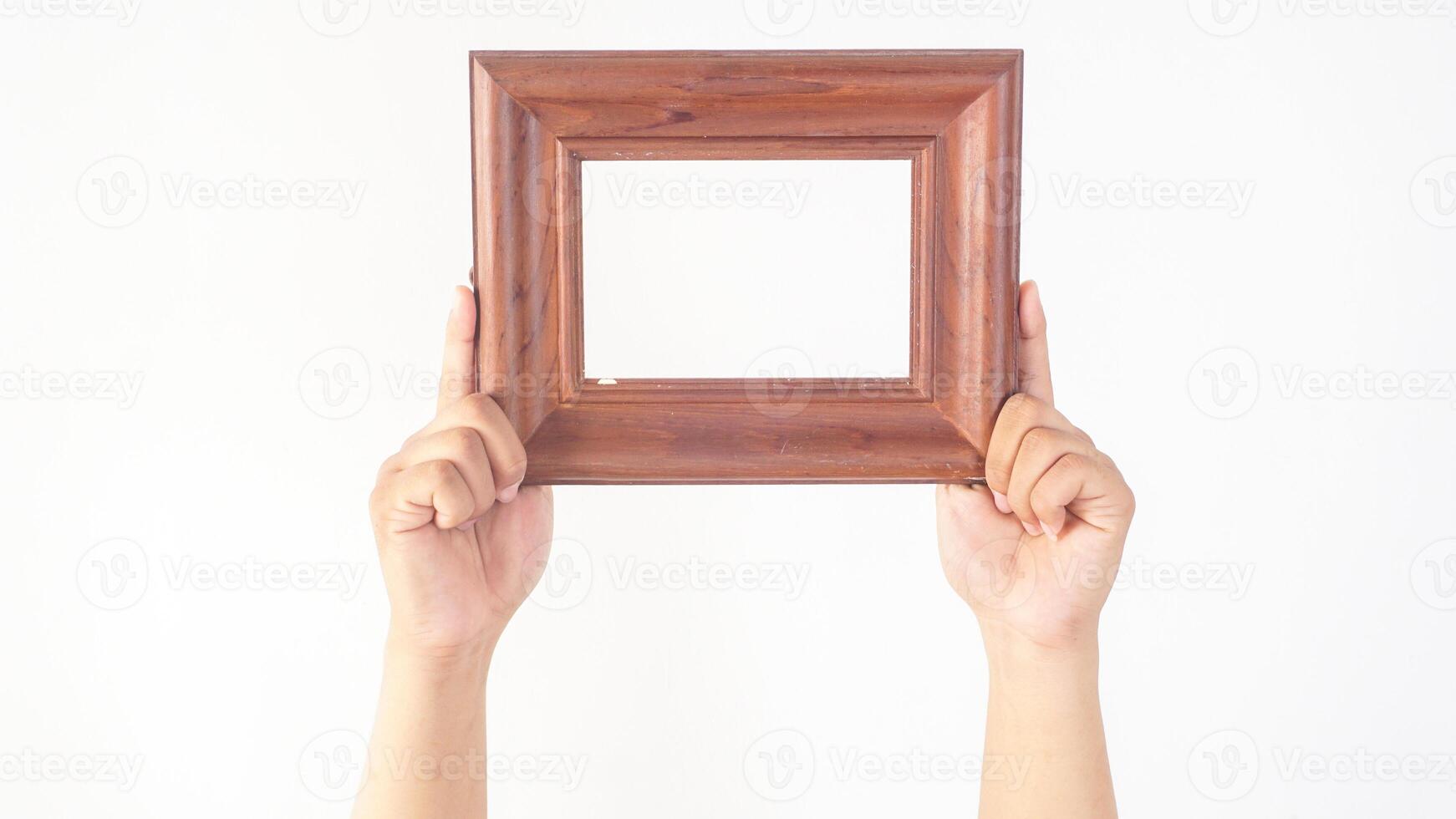 Hand holding blank brown wood photo frame isolated on white background