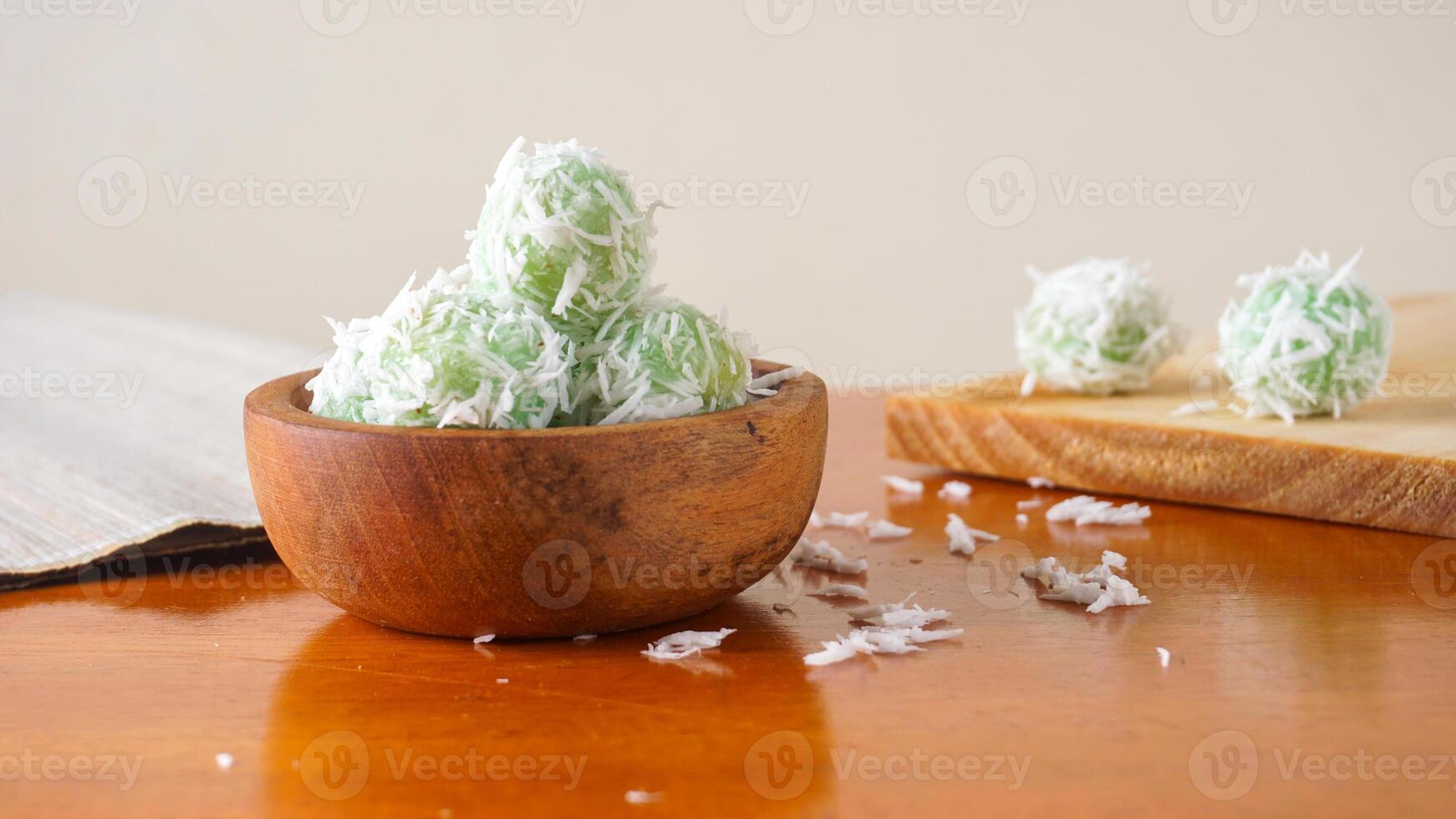 Klepon is a traditional Indonesian snack made from green sticky rice balls on wooden bowl isolated on white background photo
