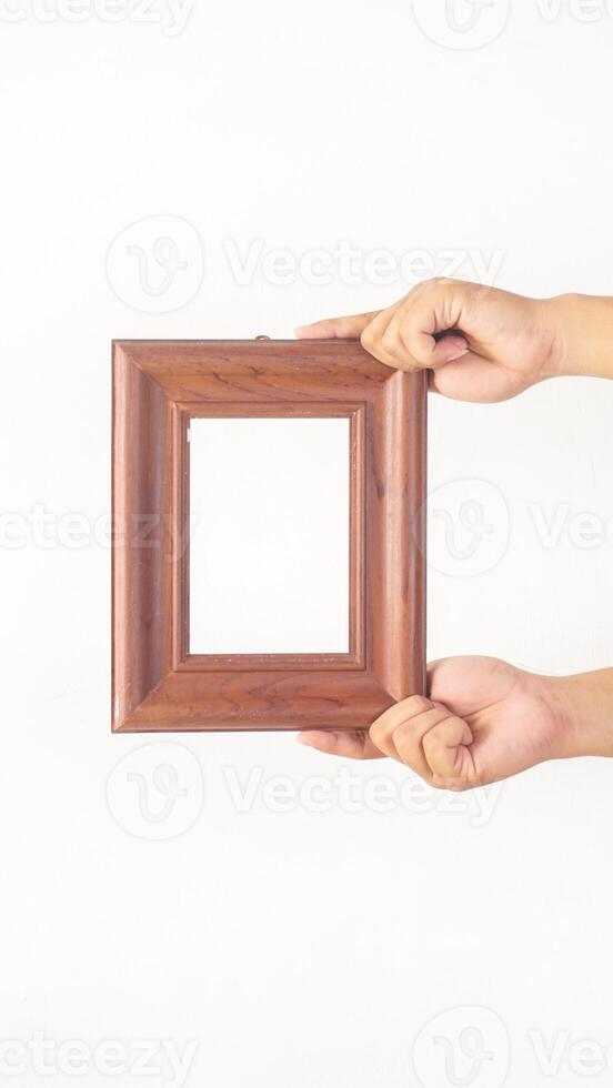 Hand holding simple brown wood picture frame isolated on white background photo