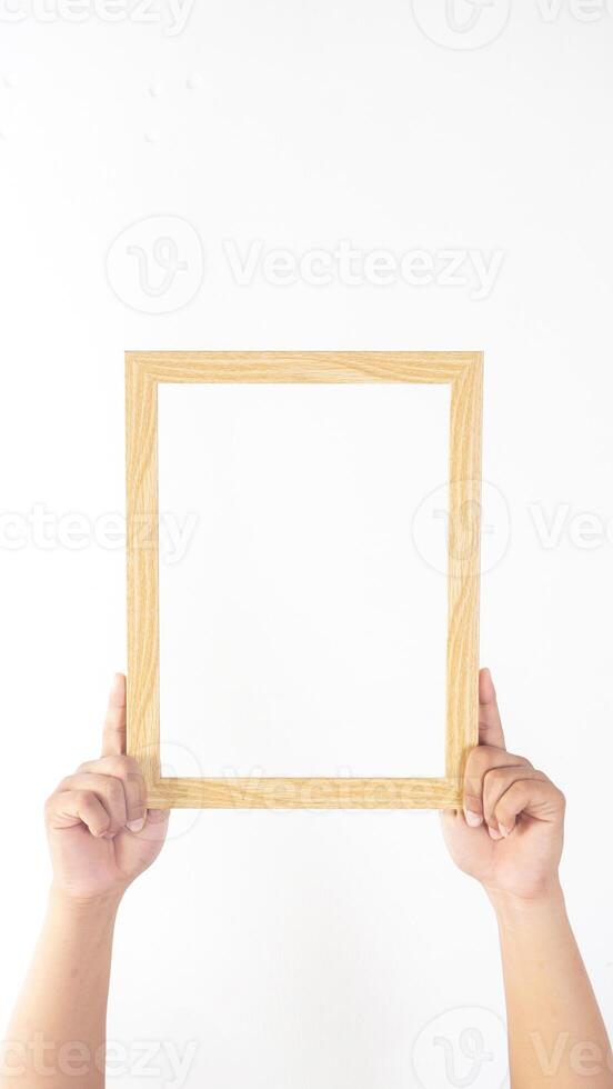 Hand holding simple wood picture frame isolated on white background photo