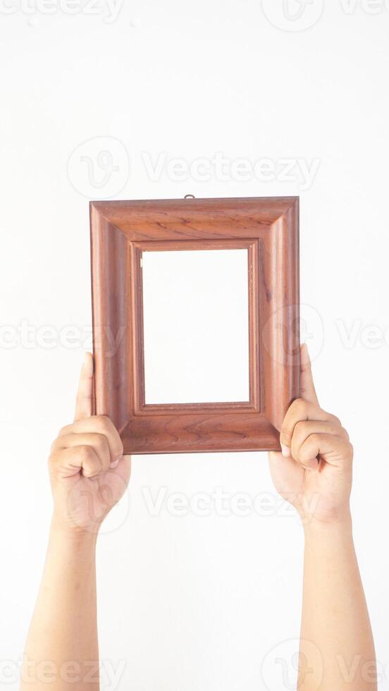 Hand holding empty brown wood photo frame isolated on white background