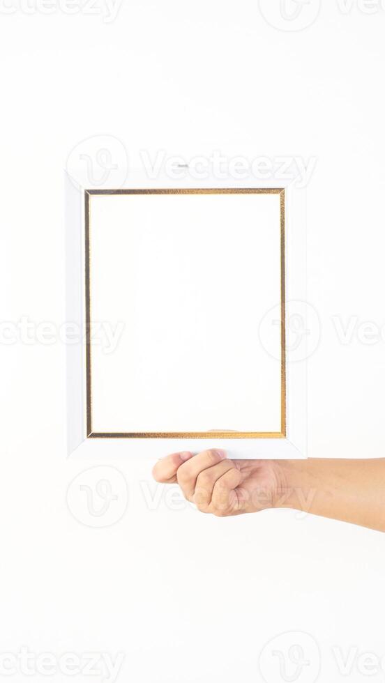 Hand holding white colored wooden picture frame isolated on white background photo