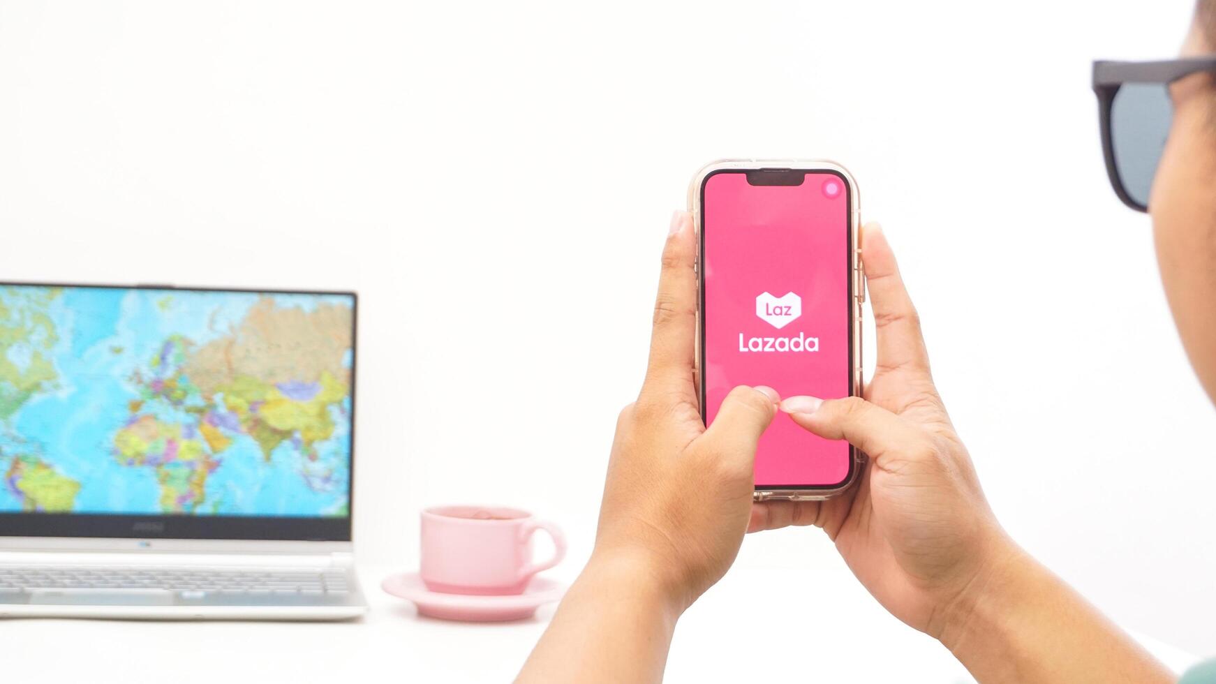 Yogyakarta, Indonesia, 2025 - Man holds smartphone showing Lazada, electronic commerce platform application on the screen isolated on white background photo