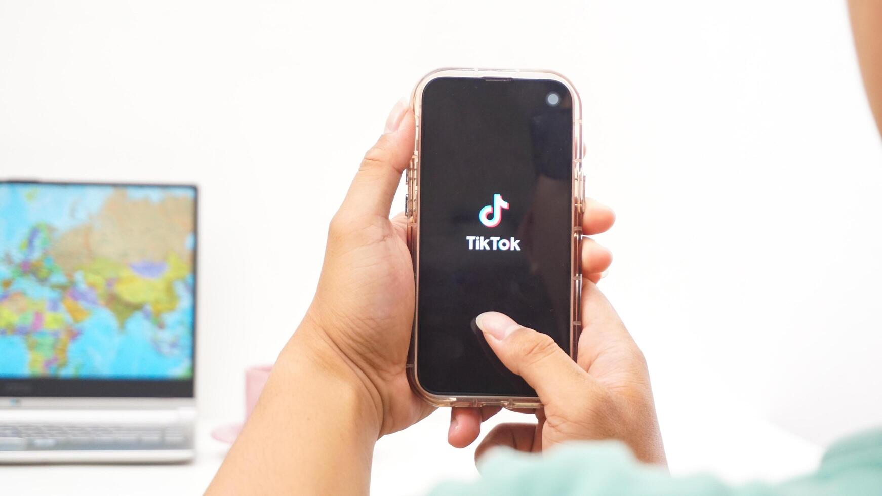 Yogyakarta, Indonesia, 2025 - Man holds smartphone with Tiktok, social and entertainment platform application on the screen isolated on white background photo