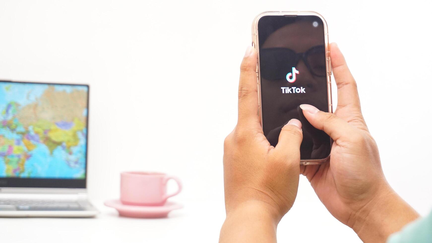 Yogyakarta, Indonesia, 2025 - Man holding smartphone showing Tiktok, social and entertainment platform application on the screen isolated on white background photo