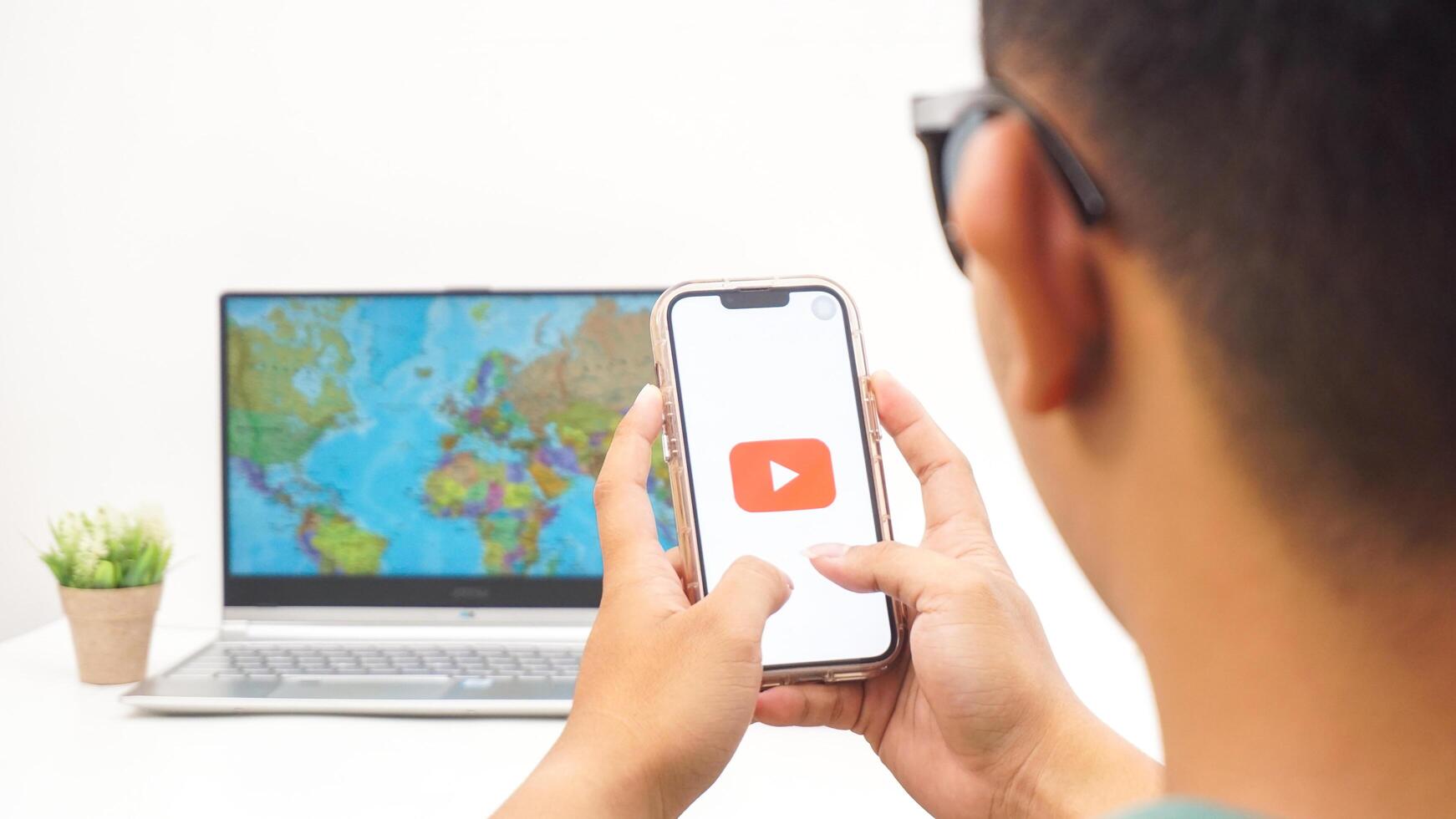 Yogyakarta, Indonesia, 2025 - Man holds smartphone with Youtube platform application on the screen isolated on white background photo