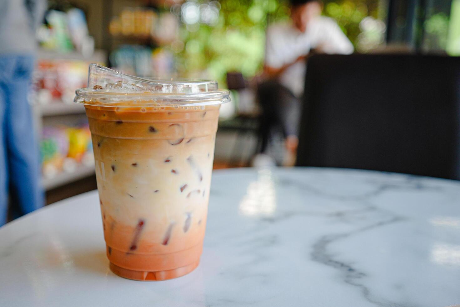 Glass of iced milk tea with coffee on marble table in coffee shop. photo