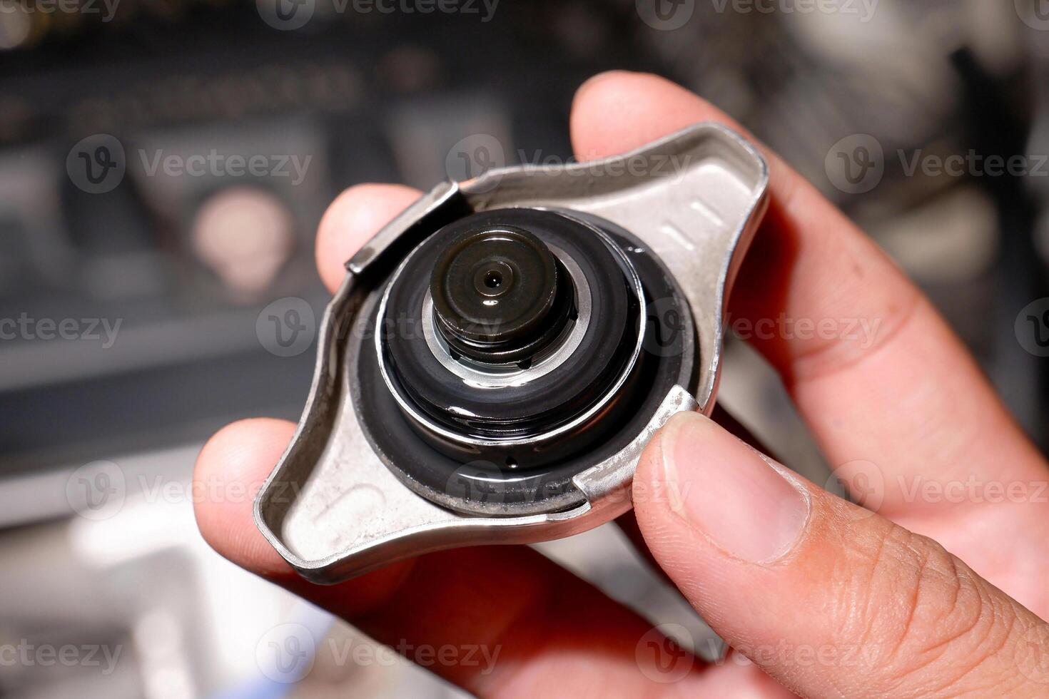 Car radiator cap, A hand holds a silver car radiator cap. Automotive maintenance and cooling system part. photo