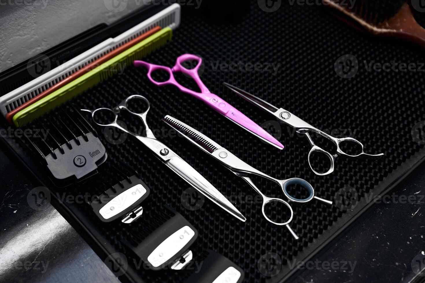 Focus on hairdressing tools arranged neatly on a black mat surface photo