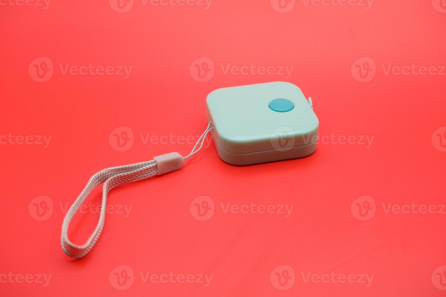 Close-up of a green soft measuring tape curled on a red background. Isolated and well-lit for use in design and advertising. photo