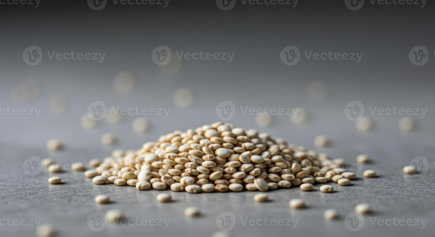 A mound of white quinoa seeds against a soft gray background is the subject of the image. photo
