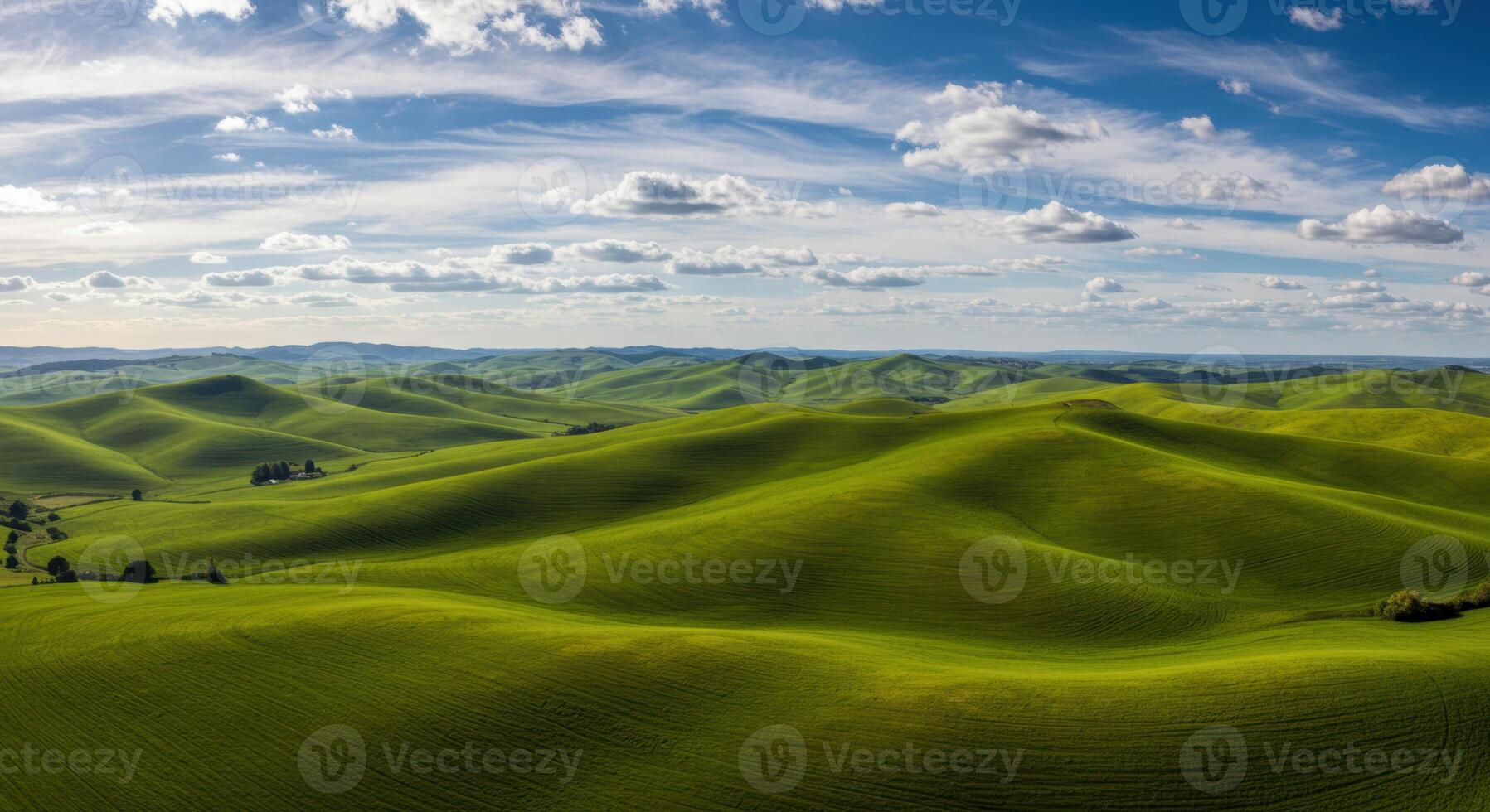 An expansive view of lush green rolling hills under a bright, partly cloudy sky. photo