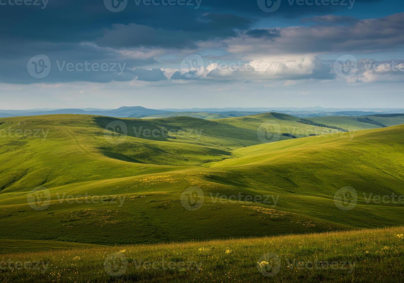 Rolling green hills stretch towards the horizon under a dramatic, cloudy sky. photo