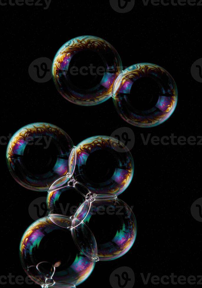 Vibrant iridescent soap bubbles float against a deep black background. photo