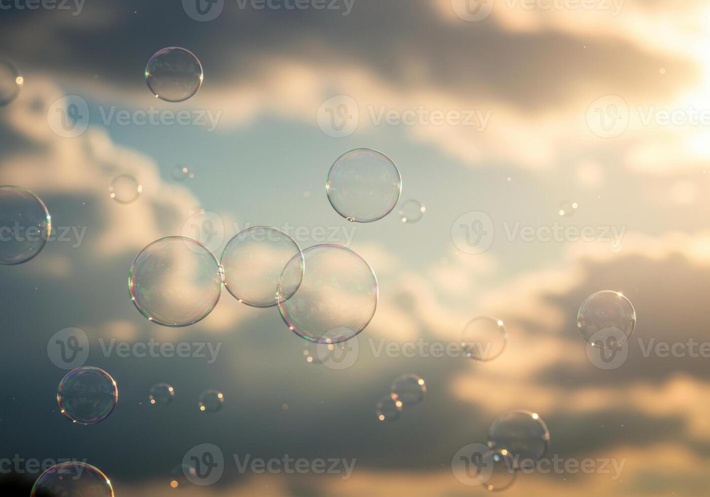 Numerous soap bubbles drift effortlessly against a backdrop of an overcast sky and sunlight. photo