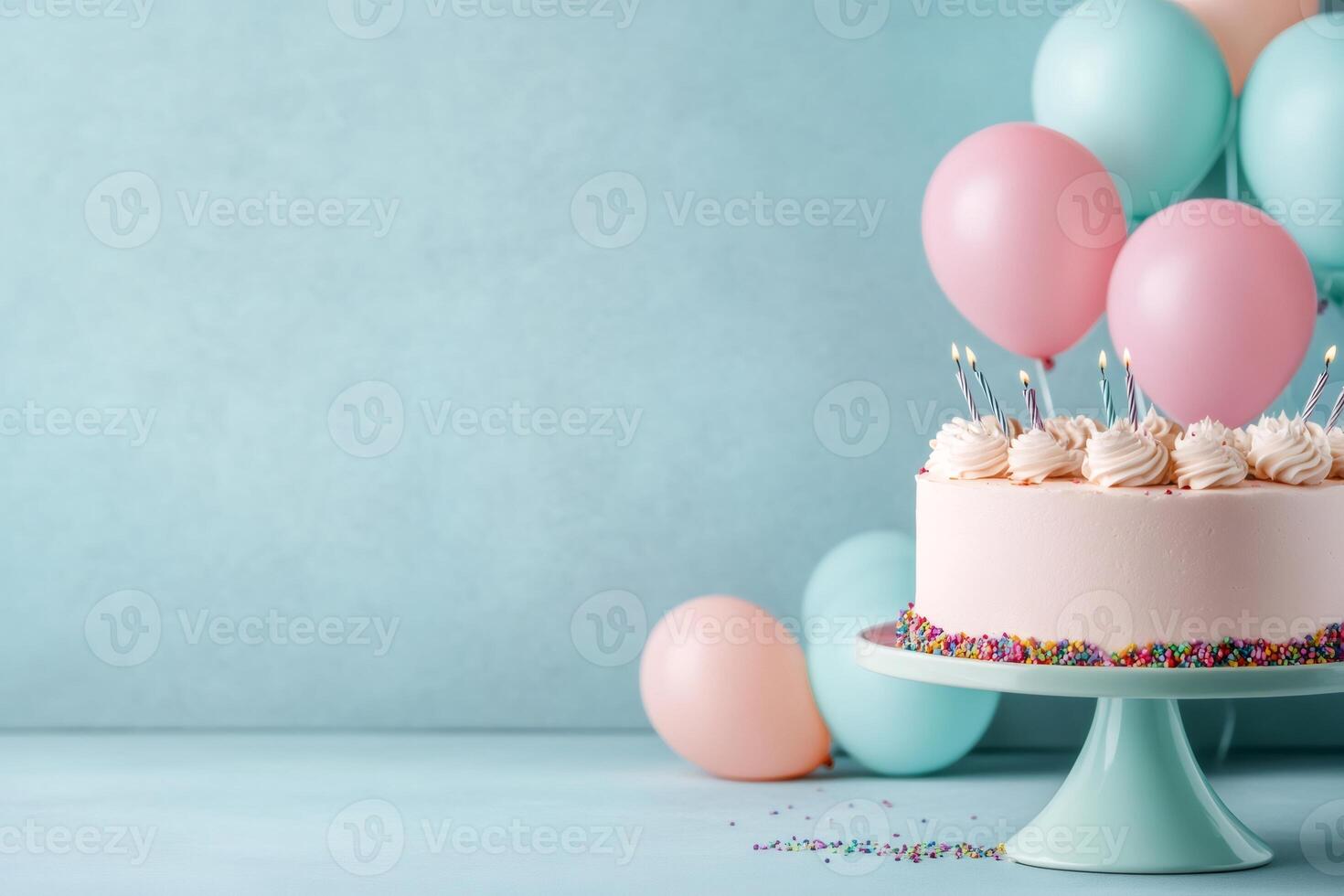 Pink birthday cake with lit candles and balloons celebrating a special occasion photo